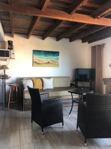 sala de estar con sofá, sillas y TV en El Mirador, en Punta del Diablo