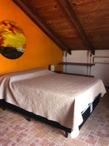 1 dormitorio con 1 cama con una pintura en la pared en El Mirador, en Punta del Diablo