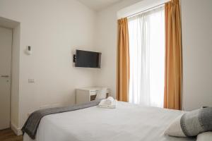 Schlafzimmer mit einem weißen Bett und einem TV an der Wand in der Unterkunft Da Fede in Rom