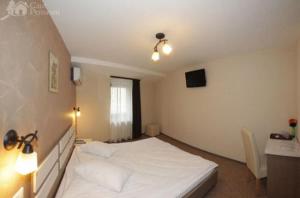 a bedroom with a large white bed and a desk at Pension Cleopatra in Târgu-Mureş