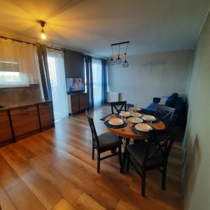 a dining room and living room with a table and chairs at Niebieski - Mala Apartamenty in Rumia
