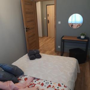 a bedroom with a bed and a table and a mirror at Niebieski - Mala Apartamenty in Rumia
