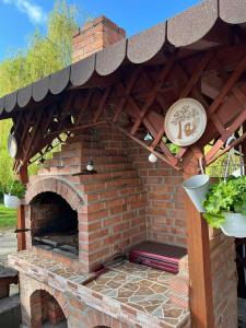 an outdoor brick oven with a roof and plants at Pensiunea Broscuta in Horezu