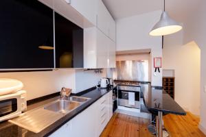 a kitchen with white cabinets and black counter tops at FLH São Jorge Castle Flat in Lisbon