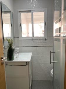 uma casa de banho com um lavatório, um WC e uma janela. em UIM Mediterraneo Alicante Wifi em Puerto de Sagunto