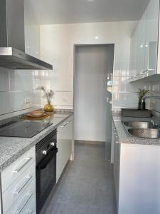 uma cozinha branca com um lavatório e uma bancada em UIM Mediterraneo Alicante Wifi em Puerto de Sagunto