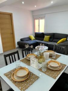 uma sala de estar com uma mesa com pratos e um sofá em UIM Mediterraneo Alicante Wifi em Puerto de Sagunto