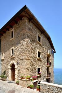 un grand bâtiment en pierre avec l'océan en arrière-plan dans l'établissement Il sogno del pescatore, à Scilla