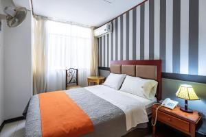 a bedroom with a bed with a striped wall at Recreo Hotel in Trujillo