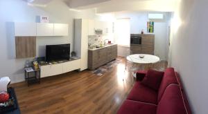 a living room with a red couch and a kitchen at Zeroventiquattro Union Apartment in Grosseto