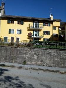 a yellow building with a fence in front of it at Le tue vacanze a Varzo, appartamento il girasole. in Varzo