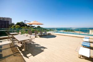 a patio with tables and chairs and an umbrella at Arena Ipanema Hotel in Rio de Janeiro