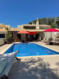 a swimming pool with umbrellas and a house at Casa Romeo y Julieta in Castro Marim