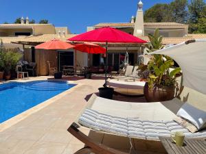 a pool with chairs and umbrellas next to a house at Casa Romeo y Julieta in Castro Marim