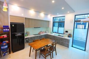 a kitchen with a wooden table and a refrigerator at Kenpi Garden Homestay - NGUYÊN CĂN, đậu nhiều ô tô in Hue