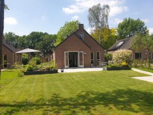 ein Backsteinhaus mit Rasen davor in der Unterkunft Ons Bosgevoel in Ewijk