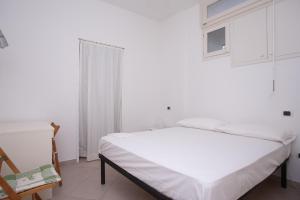 a white bedroom with a bed and a chair at N236 - Numana, bilocale vista mare nel cuore del paese in Numana