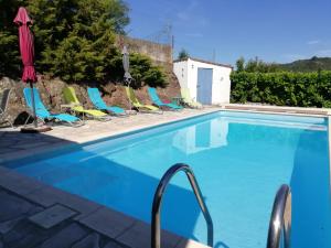 una piscina con sillas y sombrilla en Gîte le pic vert, en Prades