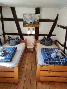 two beds in a room with wooden floors at Gemütliche Gästezimmer in einem neu sanierten Fachwerkhaus in Sachsenheim