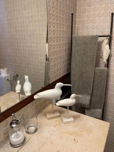 two white birds sitting on a counter in front of a mirror at Lovely 2 bedroom with a pool in front of the beach in Sesimbra