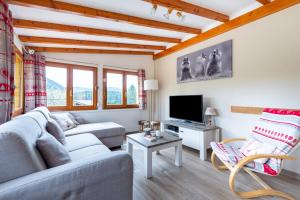 a living room with a couch and a tv at Le Repère Des Marmottes in Xonrupt-Longemer