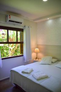 a bedroom with a large white bed with a window at Suites Prime Itamambuca in Ubatuba