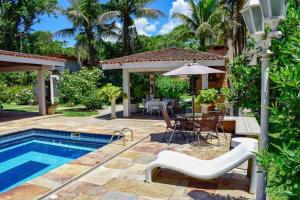 a backyard with a pool and a table and chairs at Suites Prime Itamambuca in Ubatuba