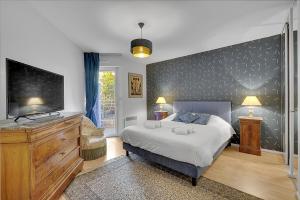 a bedroom with a large bed and a flat screen tv at LES JARDINS DE L'OLYMPE - Appartement lumineux de 137m2 in Toulouse