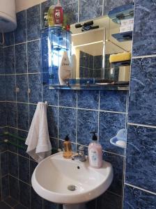 a blue tiled bathroom with a sink and a mirror at Prespa`s Balcony Guesthouse in Gorica e Vogël