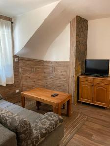 ein Wohnzimmer mit einer Couch, einem Tisch und einem Fernseher in der Unterkunft Vila NADJA in Kopaonik