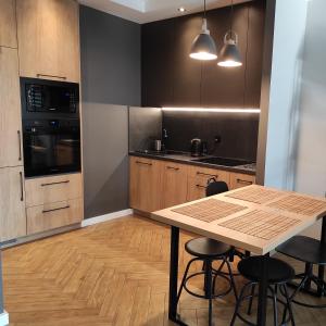 a kitchen with a wooden table and some chairs at Apartament J Towers z widokiem na jezioro in Ełk