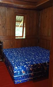 ein blaues Bett in einem Zimmer mit Fenster in der Unterkunft Hotel Agrowisata Kopeng Gunungsari in Kopeng