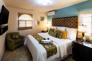 een slaapkamer met een groot bed en een stoel bij Coromuel Condo in Cabo San Lucas