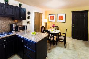een keuken met zwarte kasten en een eetkamer met een tafel bij Coromuel Condo in Cabo San Lucas