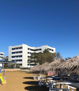 una spiaggia con tavoli e ombrelloni di paglia e un edificio di Columbus Vista Mare a Bibione Altre 4 foto