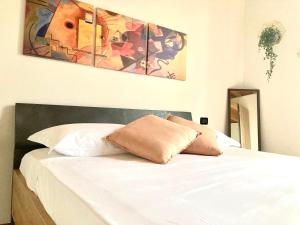 ein Schlafzimmer mit einem weißen Bett und einem Gemälde an der Wand in der Unterkunft Casa degli Ulivi in Padenghe sul Garda