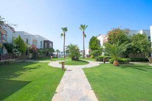a park with grass and palm trees and buildings at Costa Luvi Hotel Bodrum - All Inclusive in Gümbet