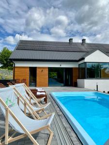 a swimming pool with two chairs and a house at KROSNA92 in Krosna