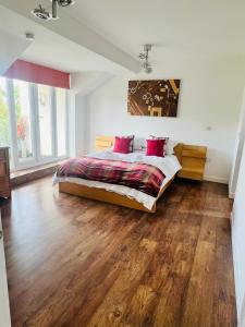 a bedroom with a bed with red pillows and wooden floors at Southview in Ganton