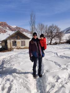 a man holding a child in the snow at Mountain Horse Trekking Guesthouse in Karakol +15 photos