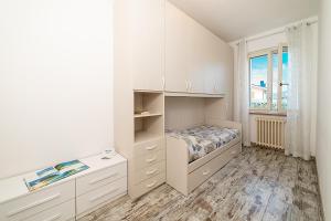 a white bedroom with a bed and a window at RUSTICO PETRA - Regarda Travel in Bardolino