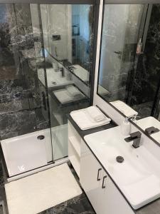 a bathroom with two sinks and a shower at Capital Towers - Apartament Modern w centrum miasta z widokiem na rzekę i park in Rzeszów +27 photos