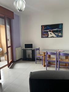 uma sala de estar com uma mesa e cadeiras e uma televisão em monolocale 2 LudoLeo 5p em Quartu SantʼElena