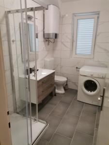 a bathroom with a sink and a washing machine at Apartman Mihaela in Rab