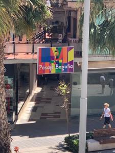a woman walking past a sign in front of a building at Kentia Rooms Torremolinos in Torremolinos