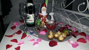 a table with a bottle of wine and wine glasses and red flowers at Prenoćište Luna 2005 in Novi Sad