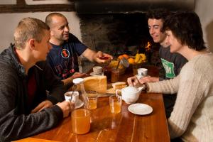 um grupo de pessoas sentadas em torno de uma mesa de madeira em Gîte Chalet La Vie Sauvage em Prats-Haut