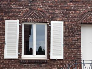 2 fenêtres avec volets blancs sur un bâtiment en briques dans l'établissement Green46, à Meerbusch