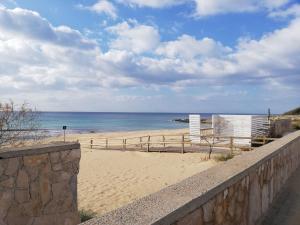 una spiaggia sabbiosa con recinzione in legno e oceano di La Conchiglia a Torre Ovo