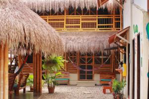 a building with a straw umbrella and chairs and tables at Coco Sänkala Hostel in Palomino